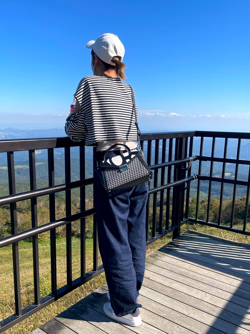 その他のトップス、ブラック系のハンドバッグ、ブルー系のデニムパンツを着用したレディースの秋コーディネートの2枚目の写真