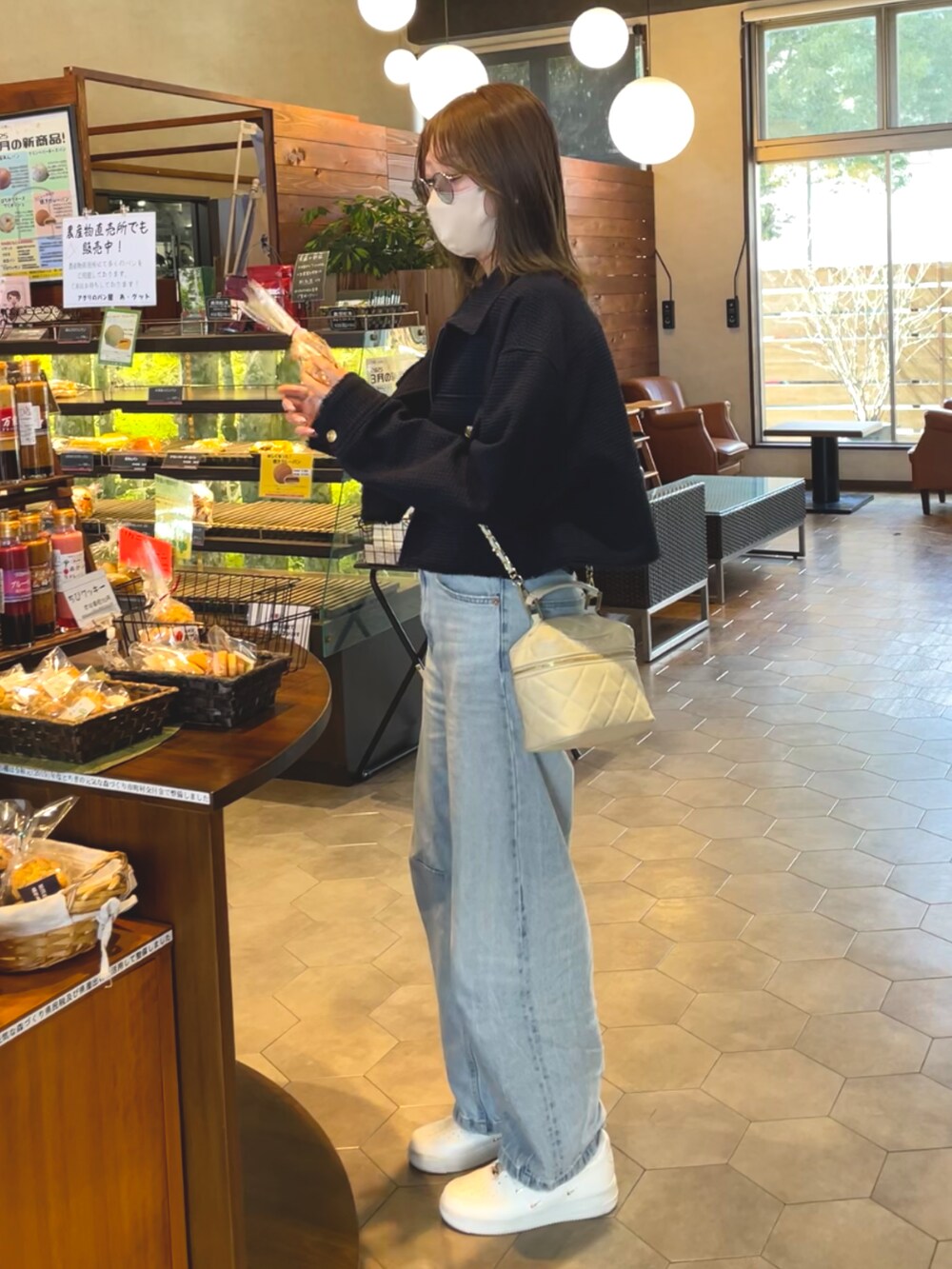 ブルー系のブルゾン、ブルー系のデニムパンツ、ベージュ系のトートバッグを着用したレディースの春コーディネートの3枚目の写真