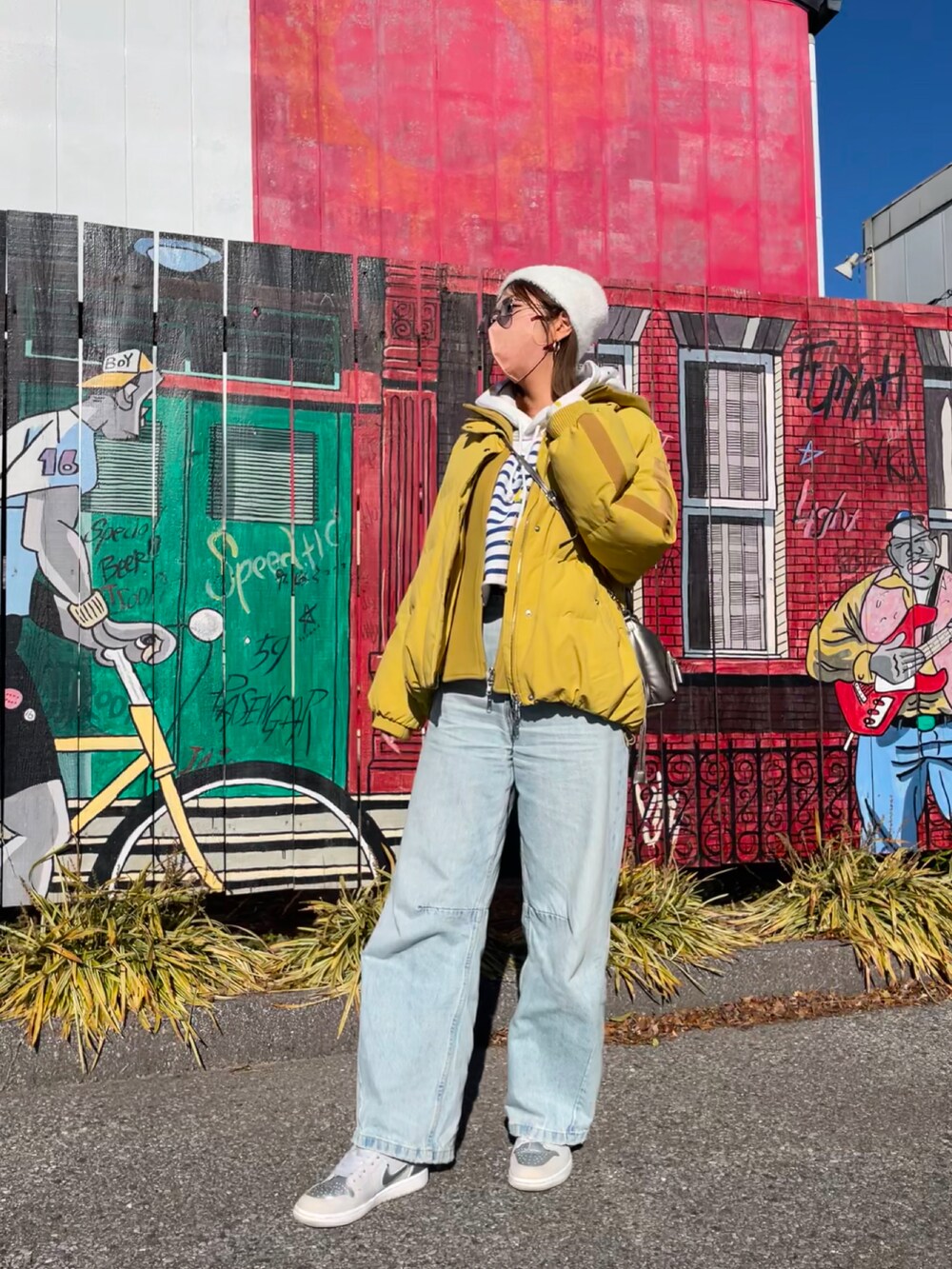 ゴールド系のショルダーバッグ、ブルー系のデニムパンツ、シルバー系のスニーカーを着用したレディースの冬コーディネートの2枚目の写真