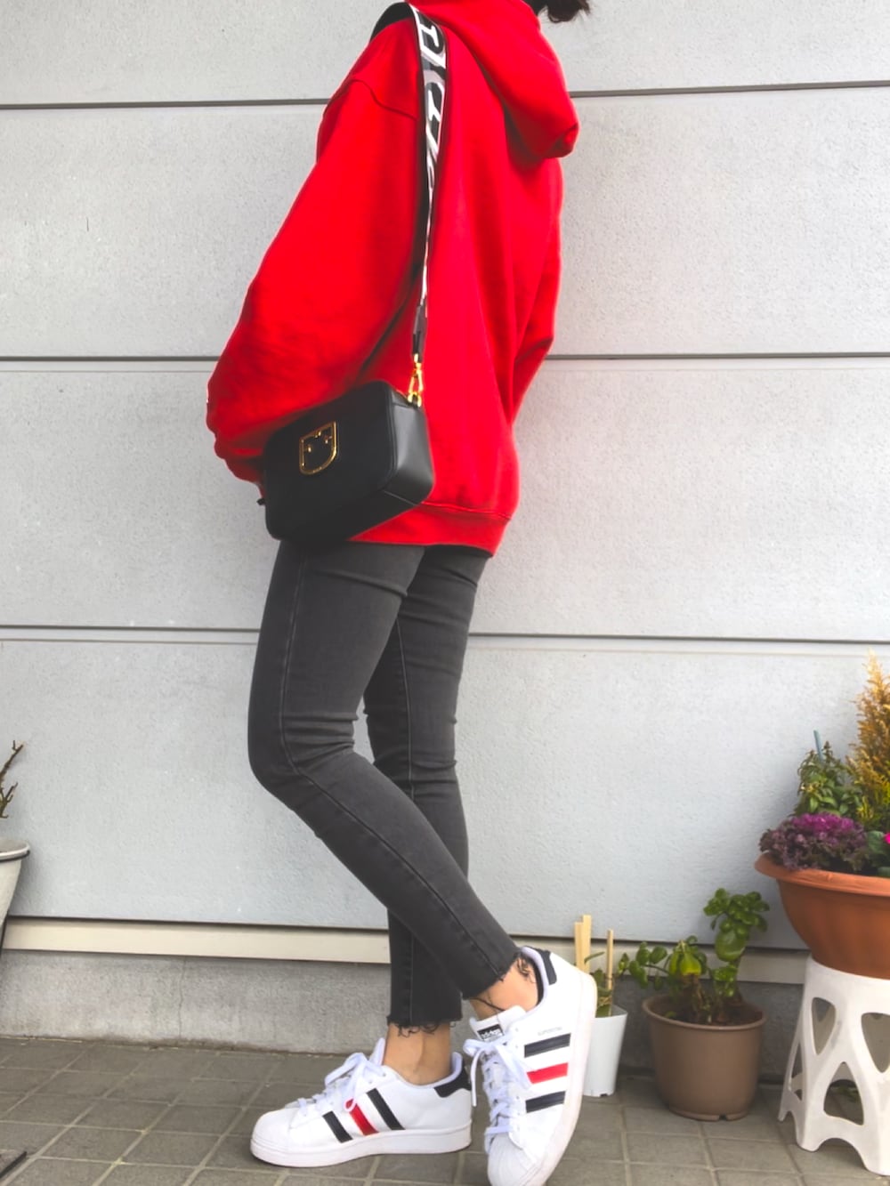 レッド系のパーカー、グレー系のデニムパンツ、ホワイト系のスニーカーを着用したレディースの春コーディネートの3枚目の写真