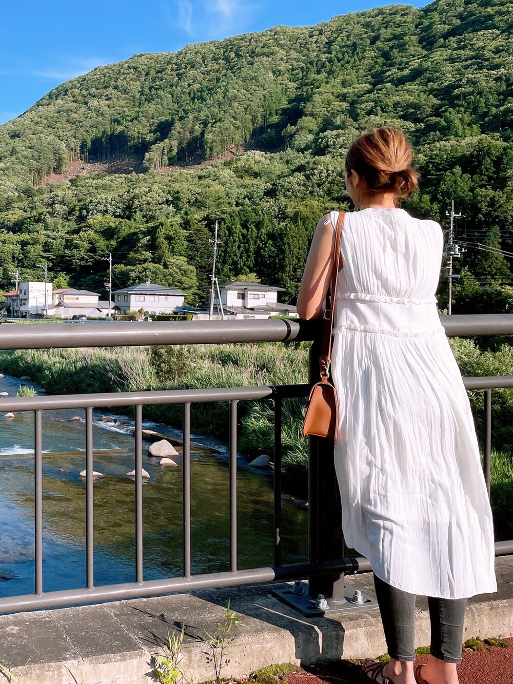 ホワイト系のトップス、ブラウン系のショルダーバッグ、グレー系のデニムパンツを着用したレディースの夏コーディネートの2枚目の写真