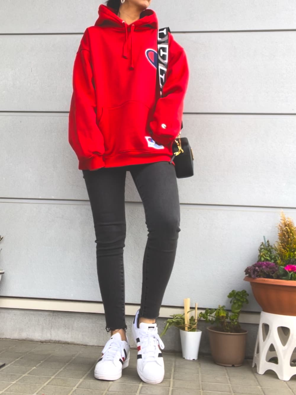 レッド系のパーカー、グレー系のデニムパンツ、ホワイト系のスニーカーを着用したレディースの春コーディネートの4枚目の写真