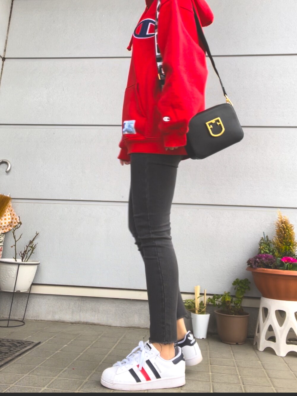 レッド系のパーカー、グレー系のデニムパンツ、ホワイト系のスニーカーを着用したレディースの春コーディネートの2枚目の写真