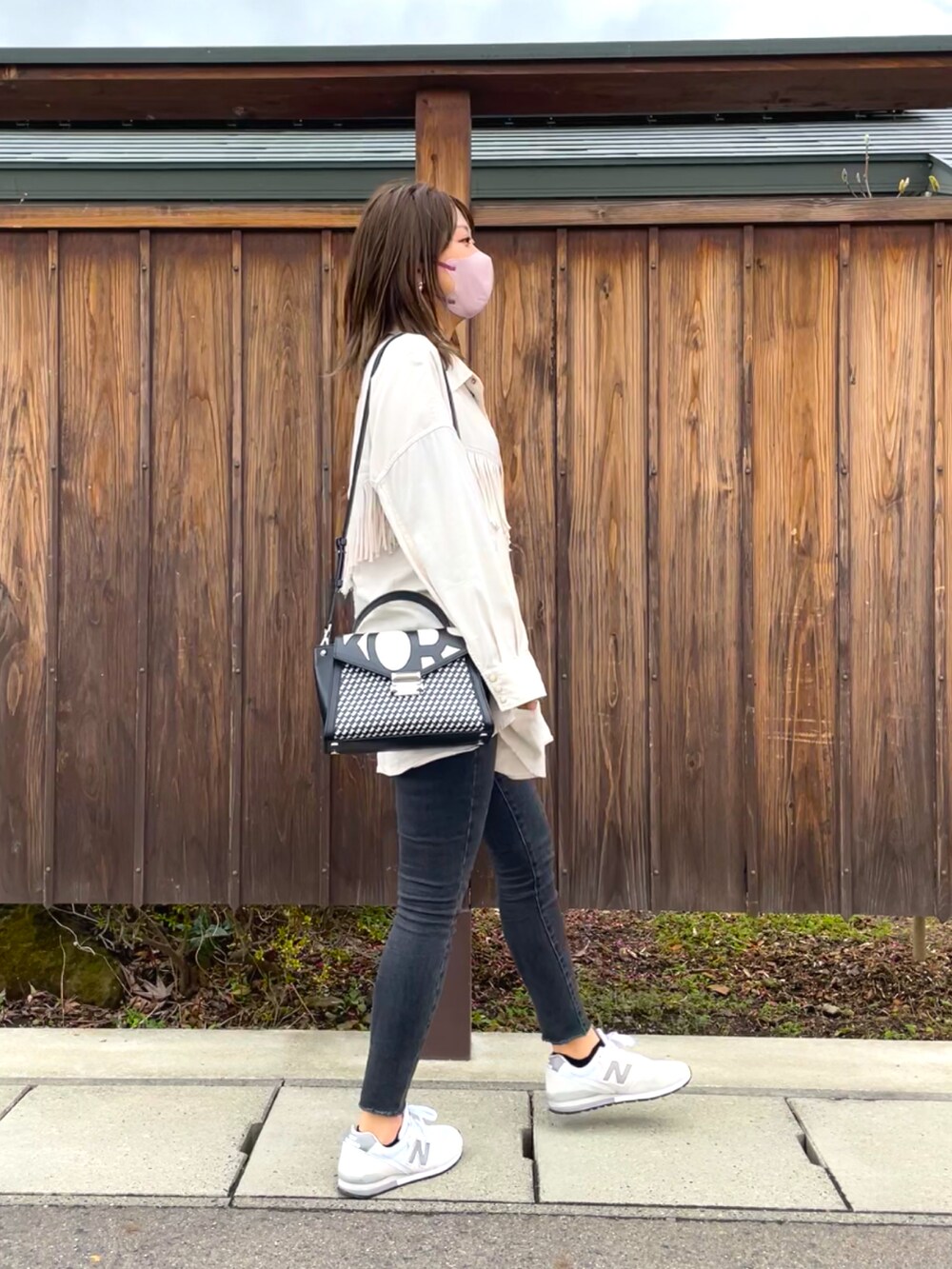 ブラック系のハンドバッグ、ホワイト系のシャツ/ブラウス、グレー系のデニムパンツを着用したレディースの春コーディネートの2枚目の写真