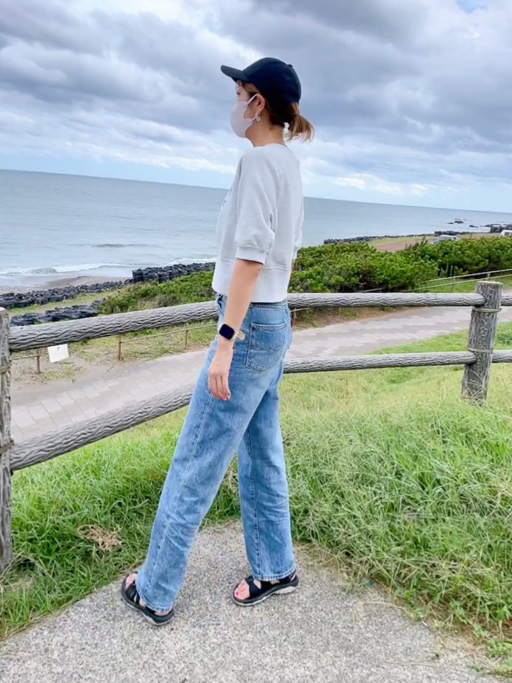 ブルー系のデニムパンツ、グレー系のTシャツ/カットソー、ブラック系のサンダルを着用したレディースの秋コーディネートの2枚目の写真