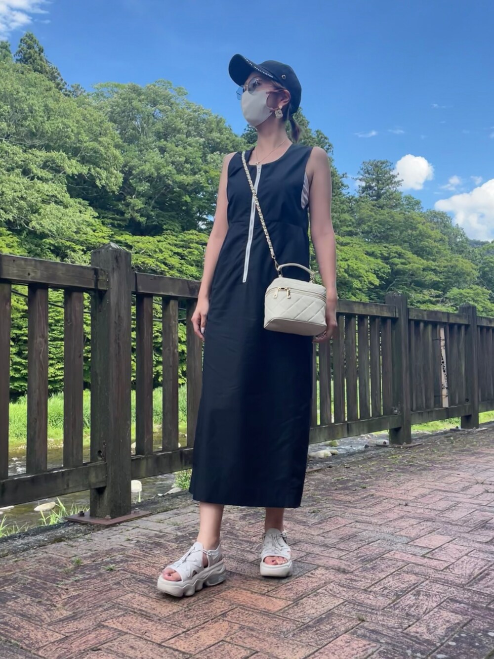 ベージュ系のトートバッグ、ブラック系のワンピース、ホワイト系のサンダルを着用したレディースの夏コーディネートの2枚目の写真