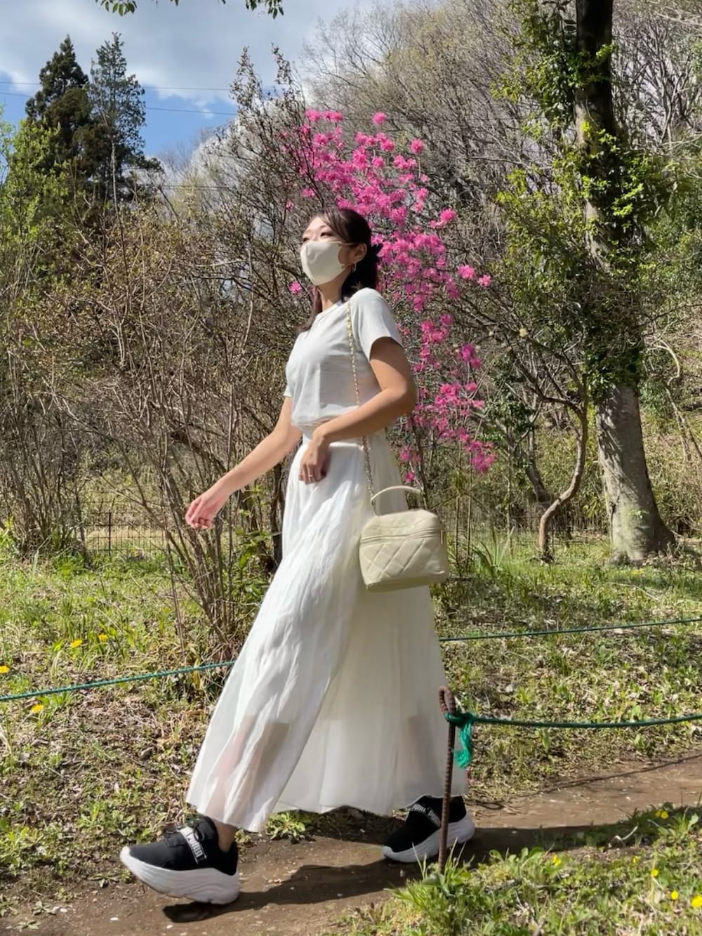 グレー系のTシャツ/カットソー、ホワイト系のスカート、ベージュ系のトートバッグを着用したレディースの春コーディネートの3枚目の写真