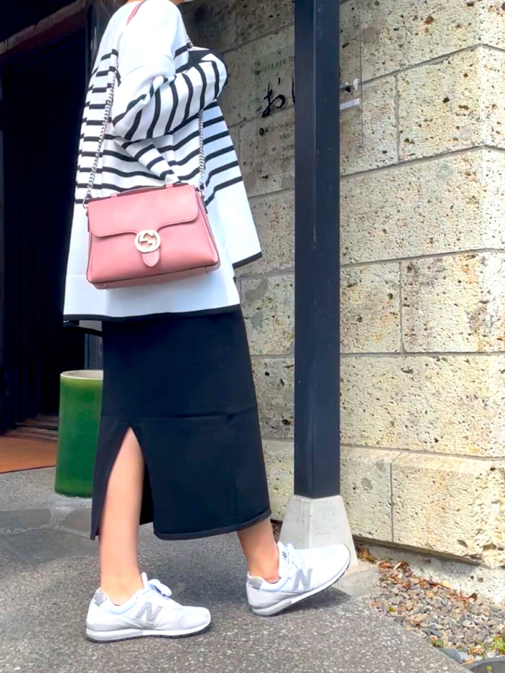 ブラック系のワンピース、ホワイト系のスニーカー、ピンク系のショルダーバッグを着用したレディースの春コーディネートの3枚目の写真