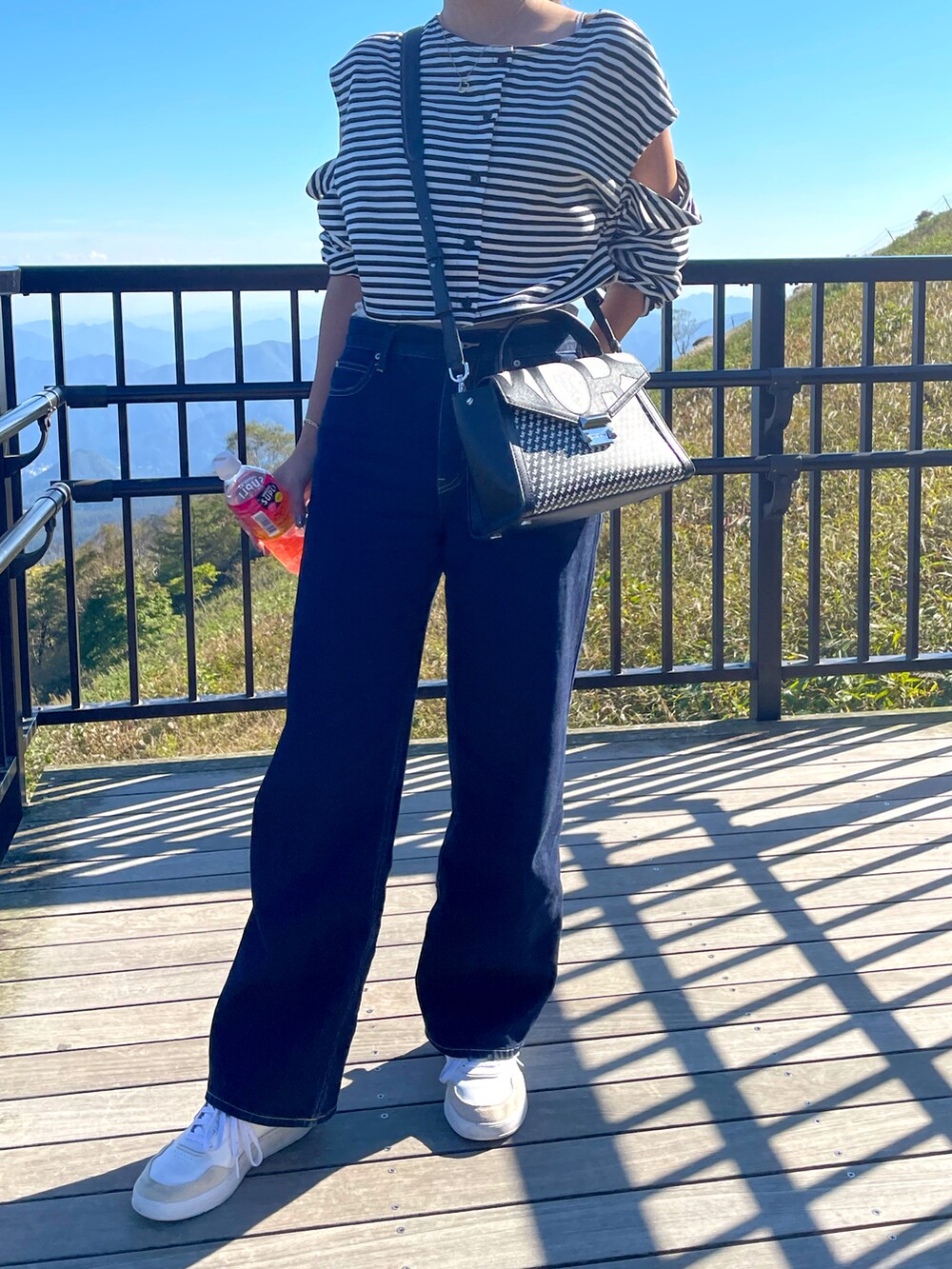 その他のトップス、ブラック系のハンドバッグ、ブルー系のデニムパンツを着用したレディースの秋コーディネートの3枚目の写真