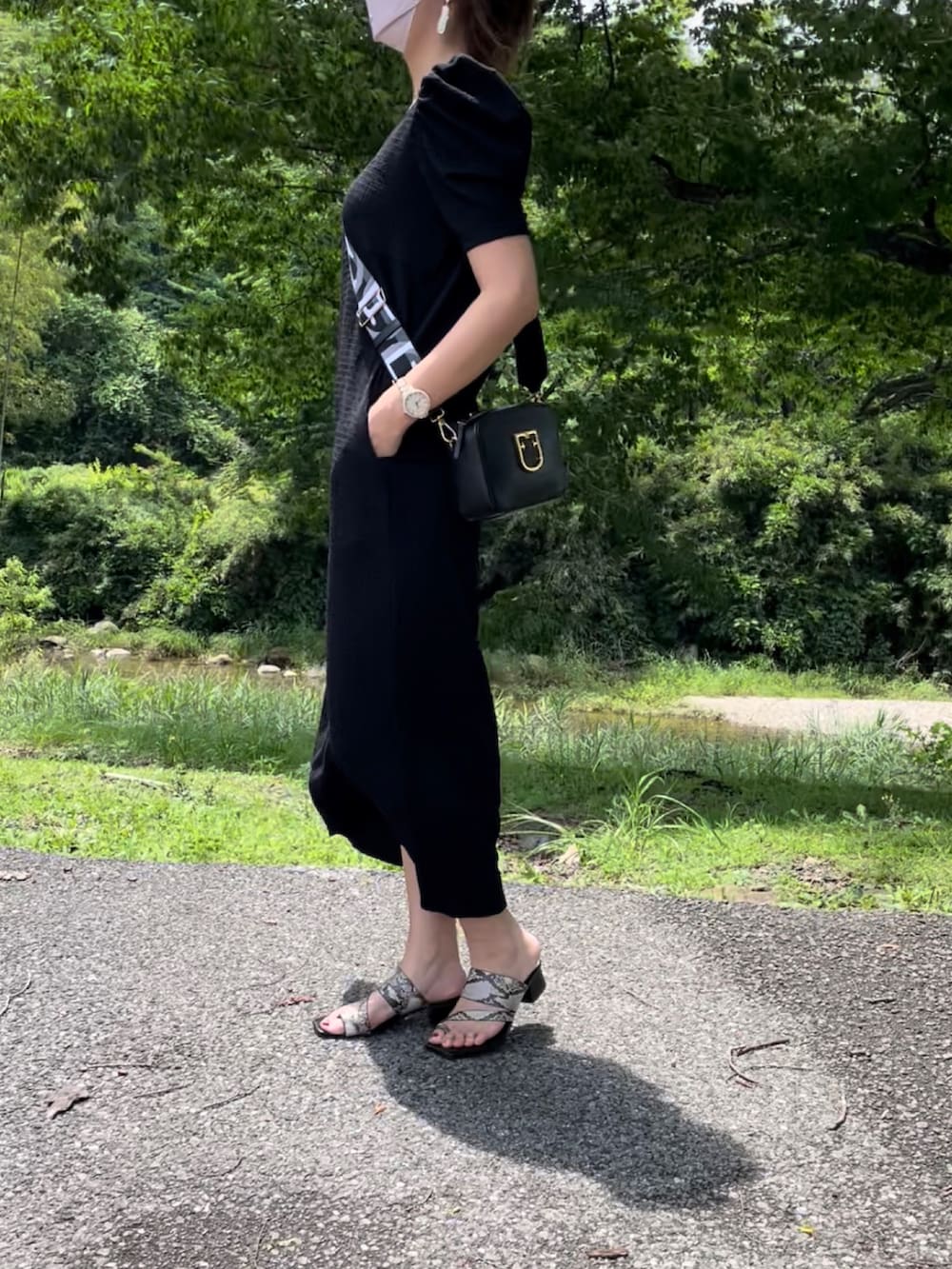 ブラック系のワンピース、ブラック系のショルダーバッグ、その他のサンダルを着用したレディースの夏コーディネートの2枚目の写真