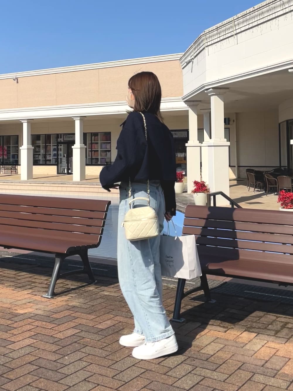 ブルー系のブルゾン、ブルー系のデニムパンツ、ベージュ系のトートバッグを着用したレディースの春コーディネートの2枚目の写真