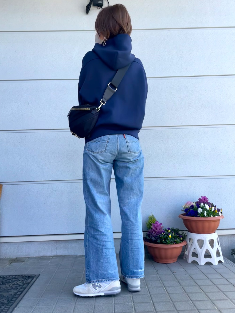 ブルー系のパーカー、ブラック系のボディバッグ/ウエストポーチ、ブルー系のデニムパンツを着用したレディースの春コーディネートの2枚目の写真
