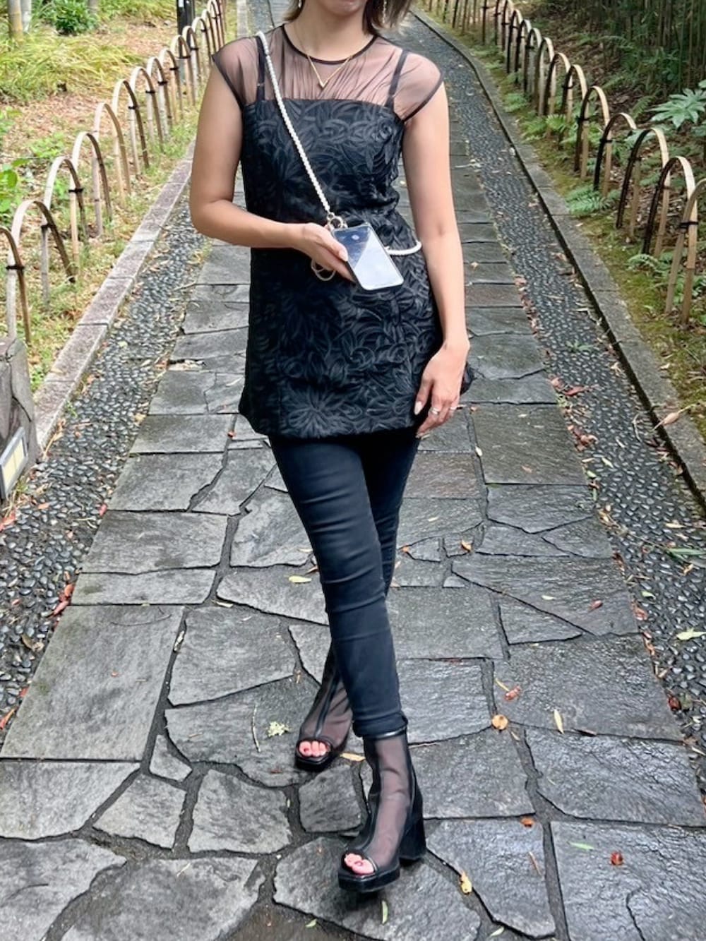 ブラック系のパンツドレス、ブラック系のサンダルを着用したレディースの秋コーディネートの2枚目の写真