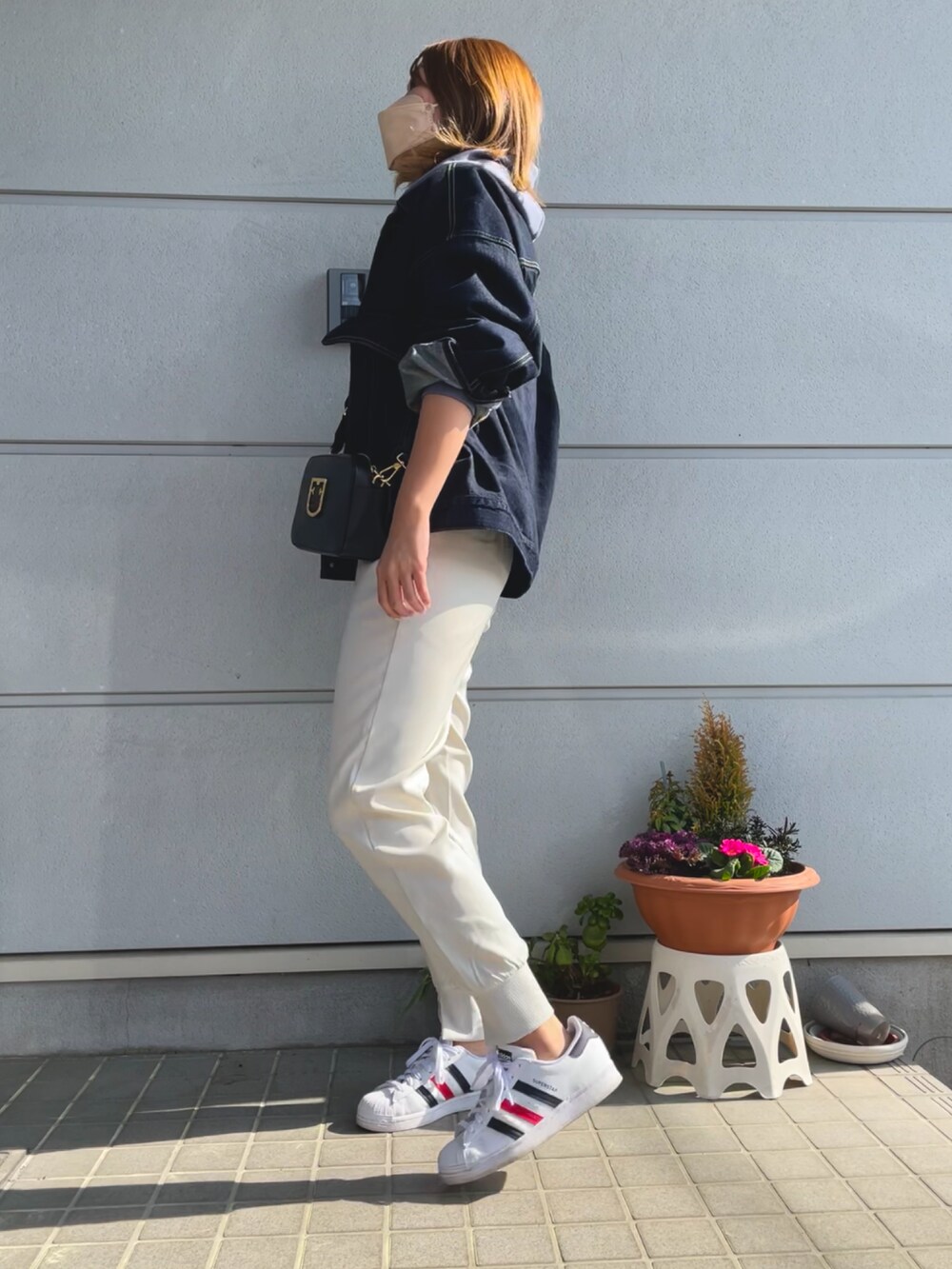 ブルー系のデニムジャケット、ブラック系のショルダーバッグ、ブルー系のパーカーを着用したレディースの春コーディネートの2枚目の写真