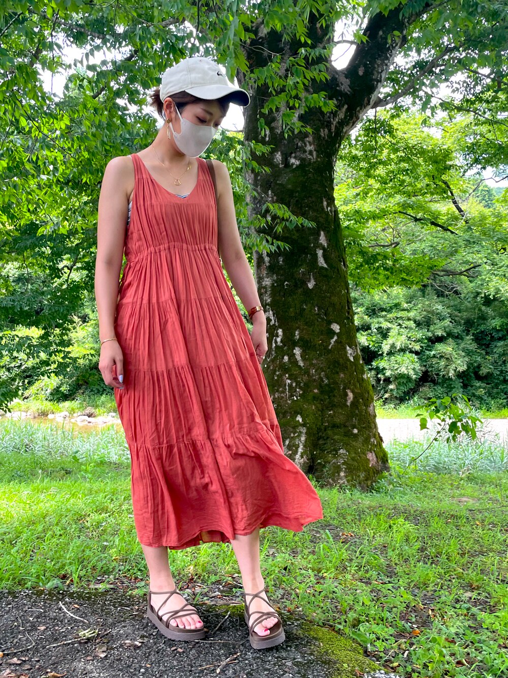 ブラウン系のかごバッグ、オレンジ系のワンピース、ブラウン系のサンダルを着用したレディースの夏コーディネートの2枚目の写真