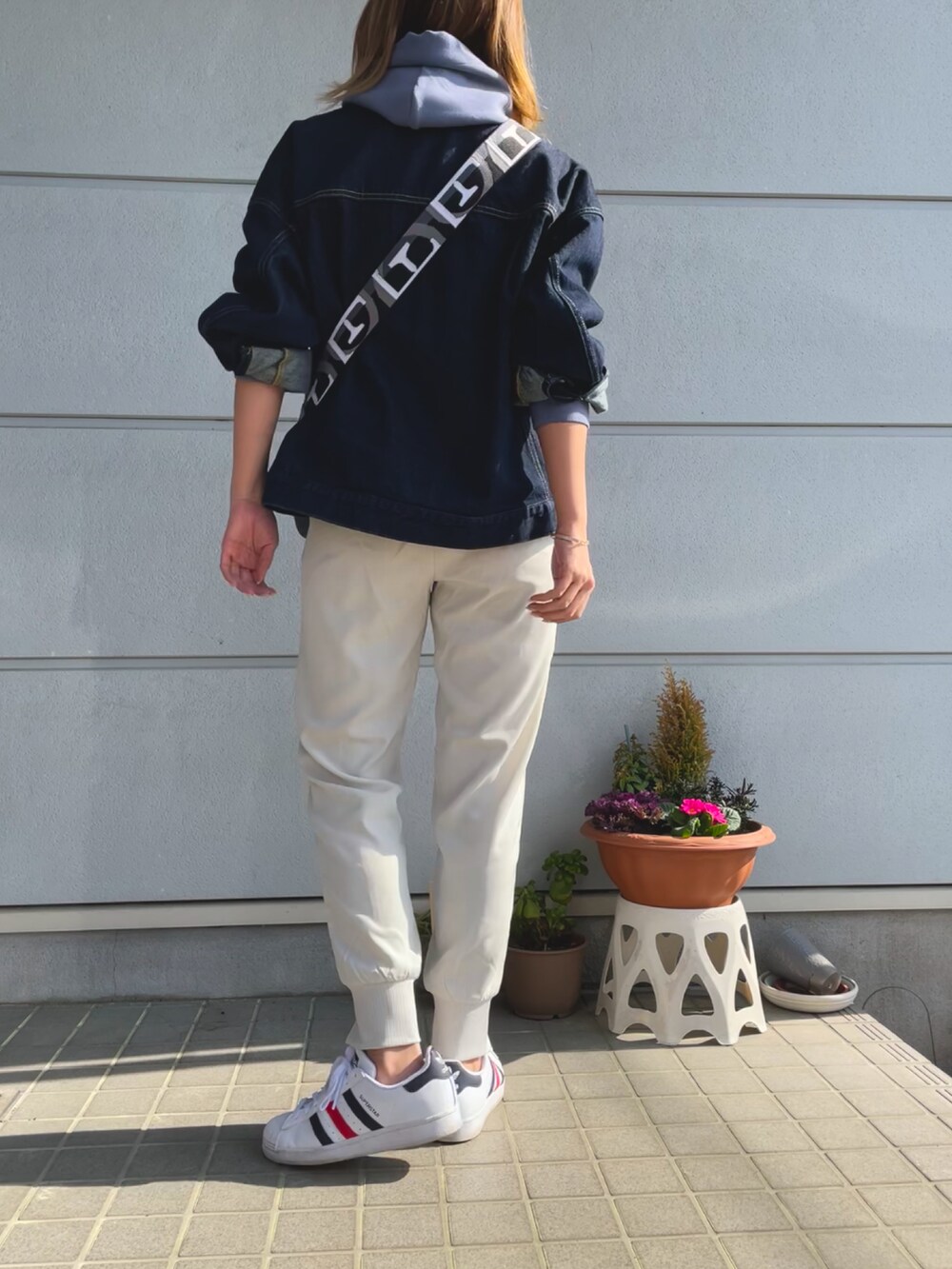 ブルー系のデニムジャケット、ブラック系のショルダーバッグ、ブルー系のパーカーを着用したレディースの春コーディネートの3枚目の写真