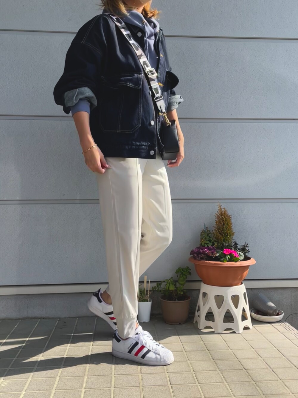 ブルー系のデニムジャケット、ブラック系のショルダーバッグ、ブルー系のパーカーを着用したレディースの春コーディネートの4枚目の写真