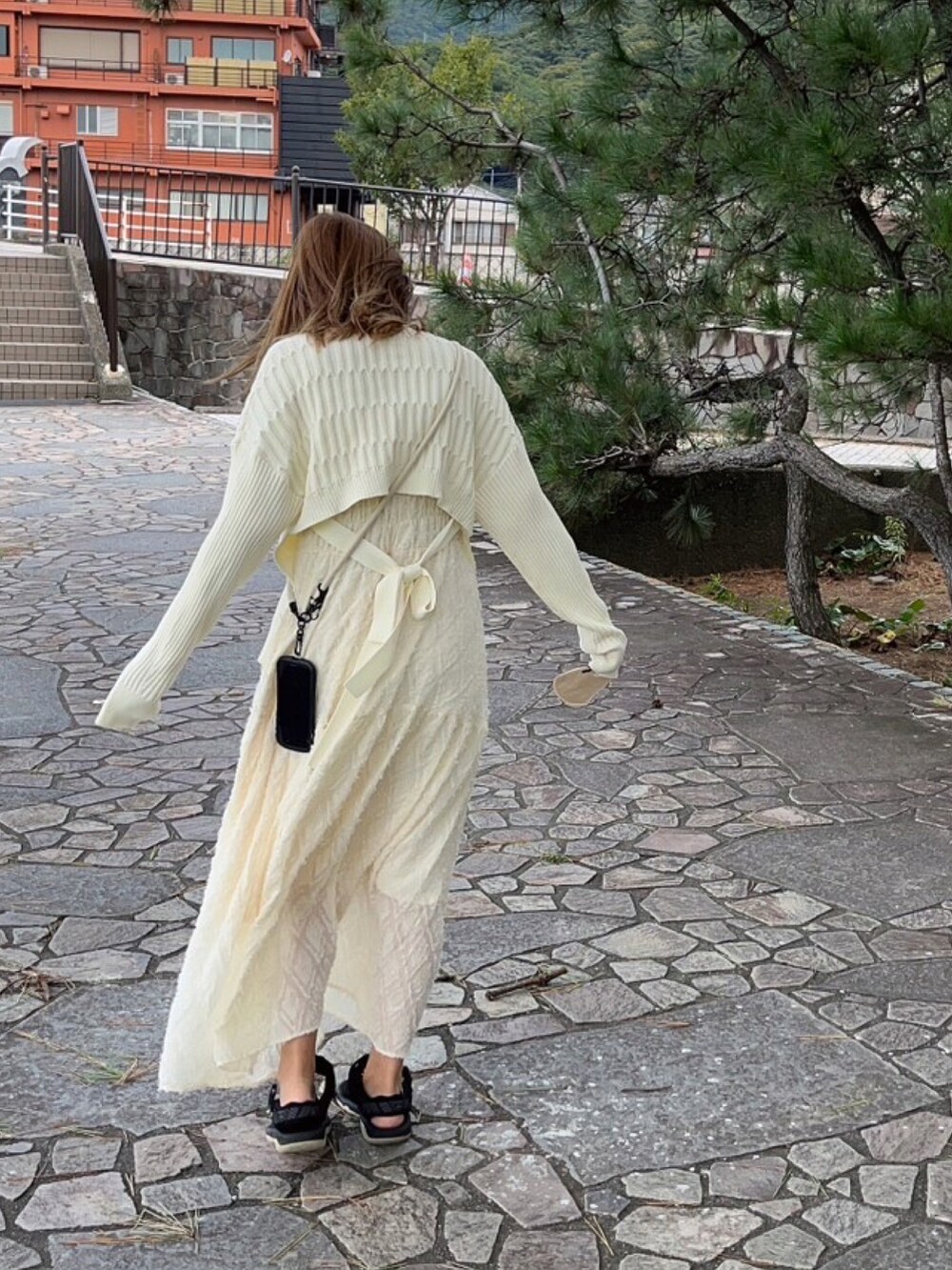 ホワイト系のカーディガン/ボレロ、ホワイト系のワンピース、ブラック系のサンダルを着用したレディースの秋コーディネートの3枚目の写真