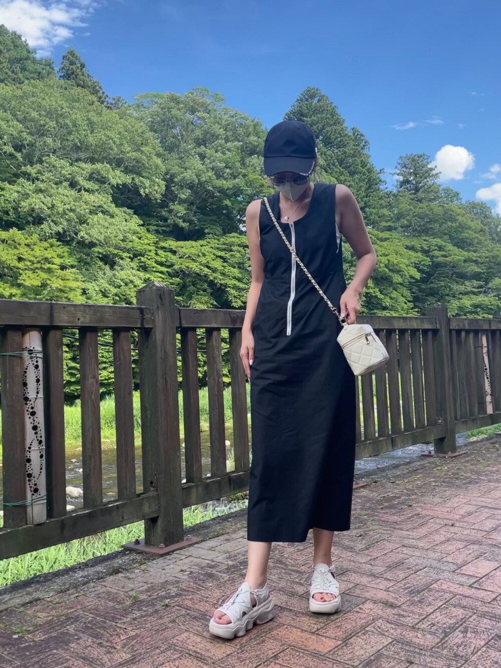 ベージュ系のトートバッグ、ブラック系のワンピース、ホワイト系のサンダルを着用したレディースの夏コーディネートの3枚目の写真