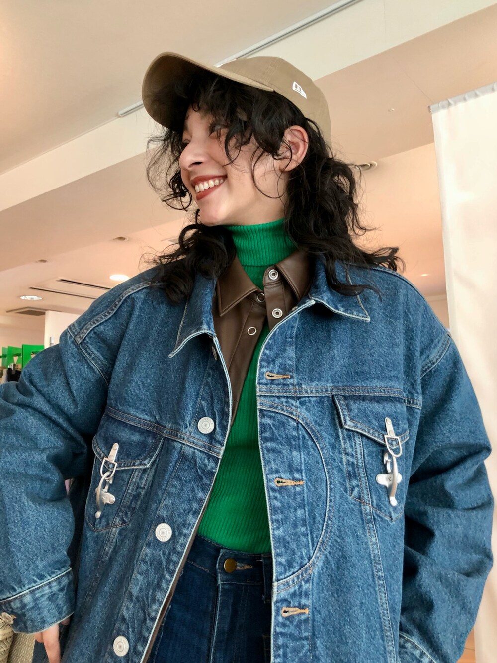 ブルー系のデニムパンツ、ホワイト系のスニーカー、グリーン系のニット/セーターを着用したレディースの冬コーディネートの4枚目の写真