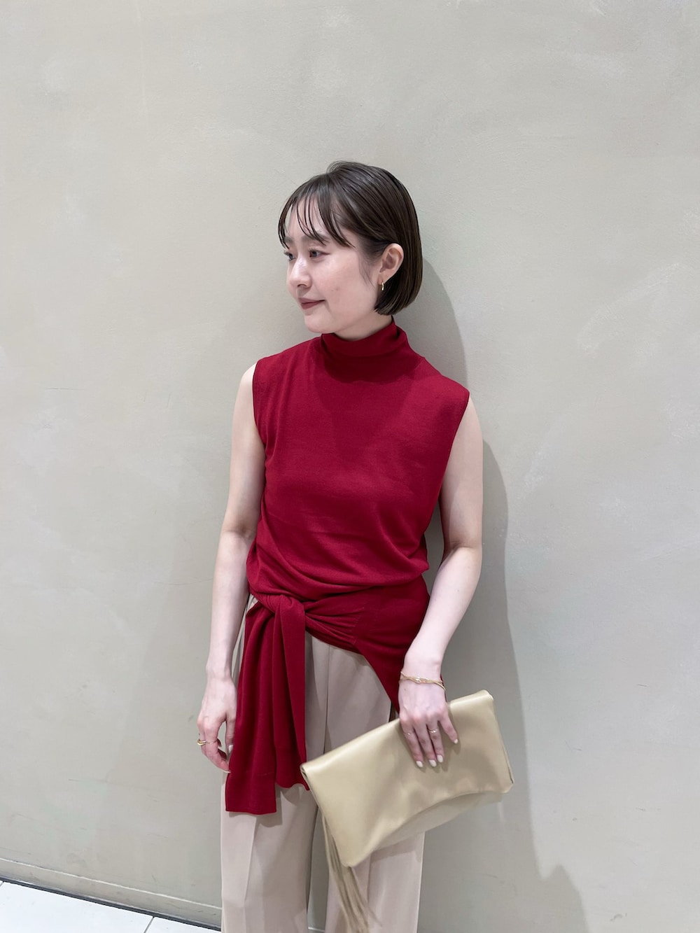 ベージュ系のスラックス、レッド系のカーディガン/ボレロ、レッド系のニット/セーターを着用したレディースの夏コーディネートの3枚目の写真