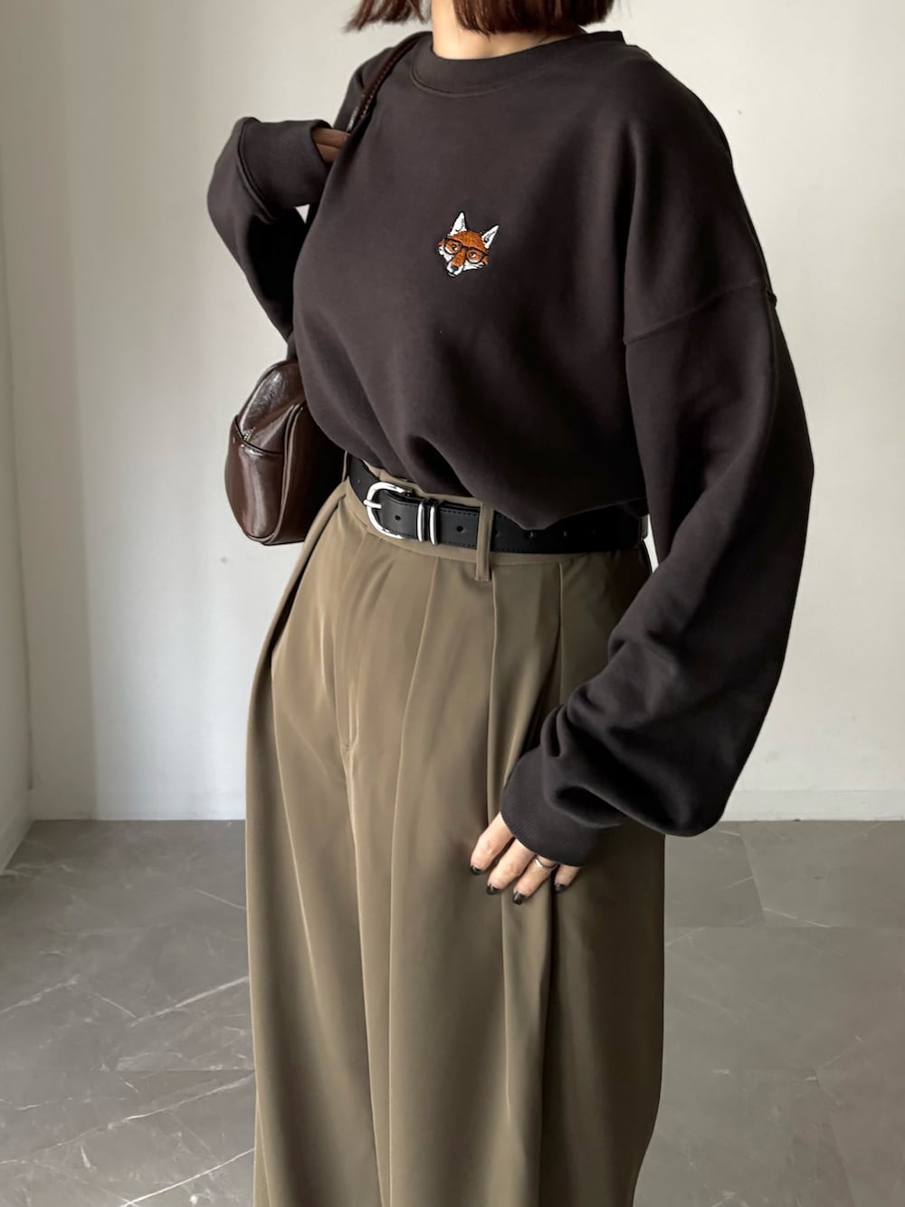 グレー系のスウェット、ブラウン系のスラックス、ブラウン系のショルダーバッグを着用したレディースの春コーディネートの2枚目の写真