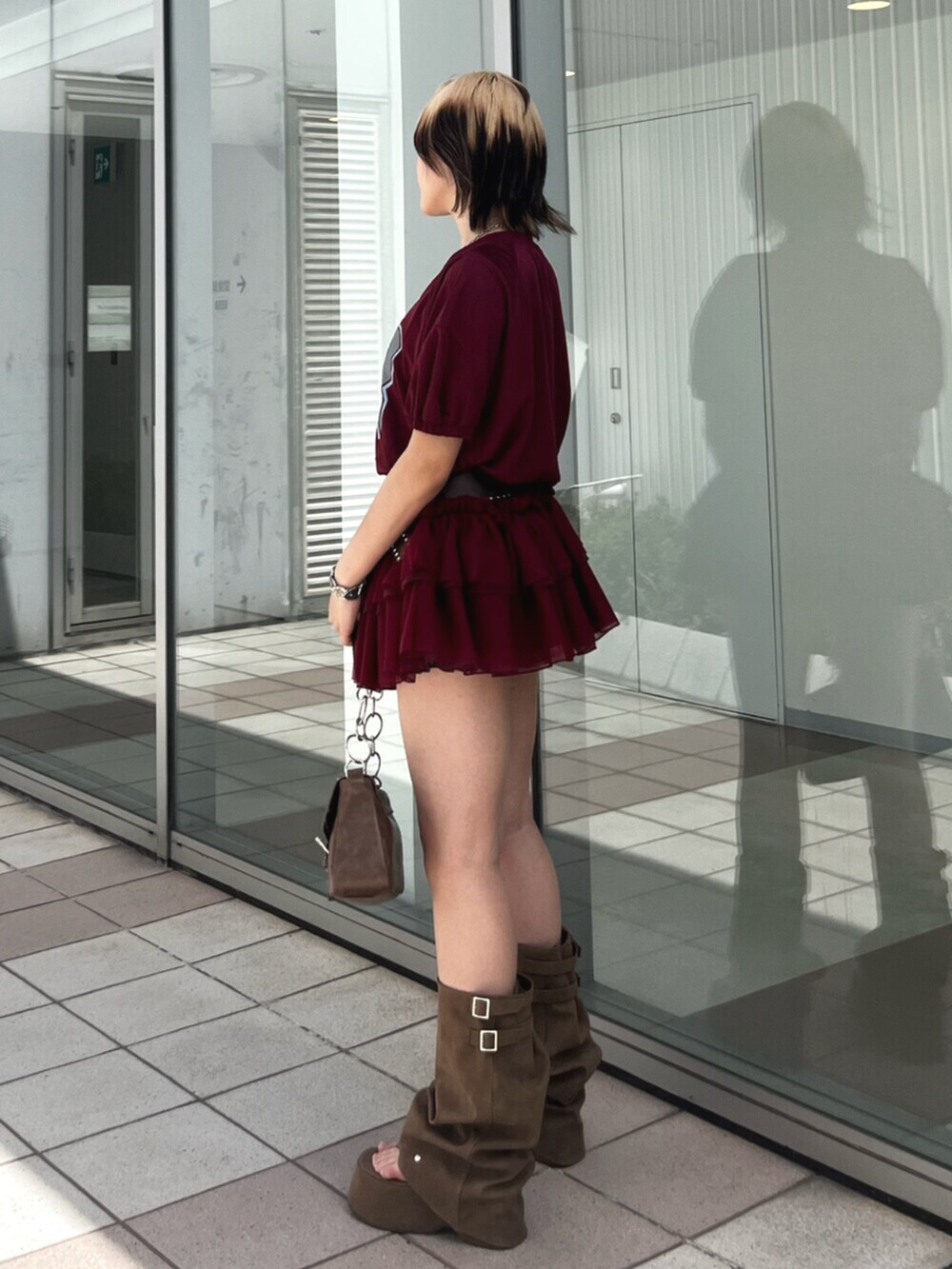 レッド系のワンピース、ブラウン系のハンドバッグ、ブラウン系のサンダルを着用したレディースの春コーディネートの4枚目の写真