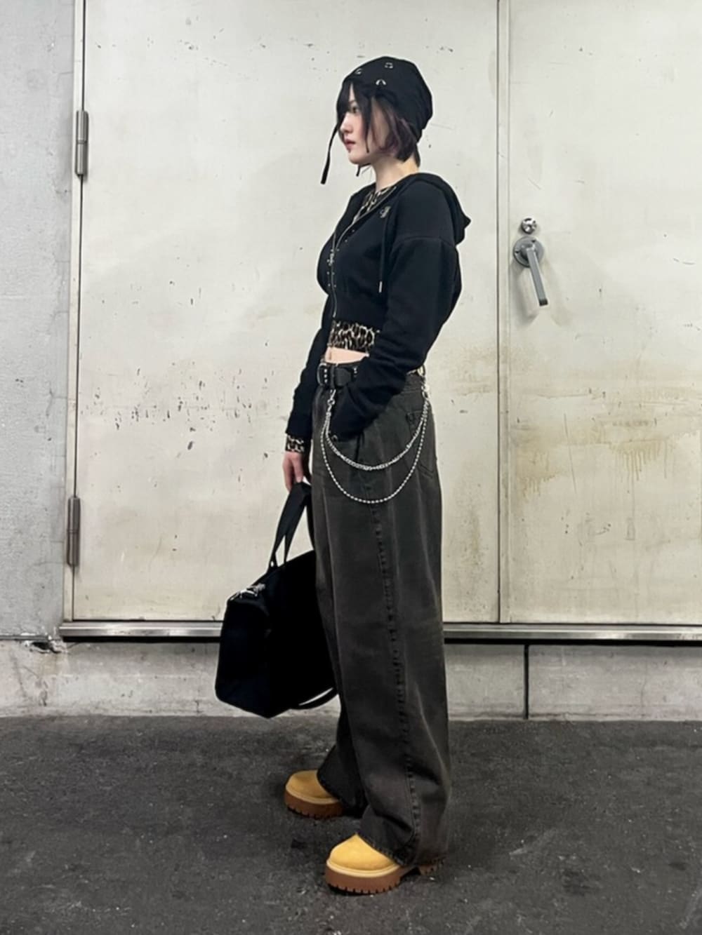 ブラック系のパーカー、ブラウン系のカーディガン/ボレロ、ブラック系のデニムパンツを着用したレディースの春コーディネートの2枚目の写真