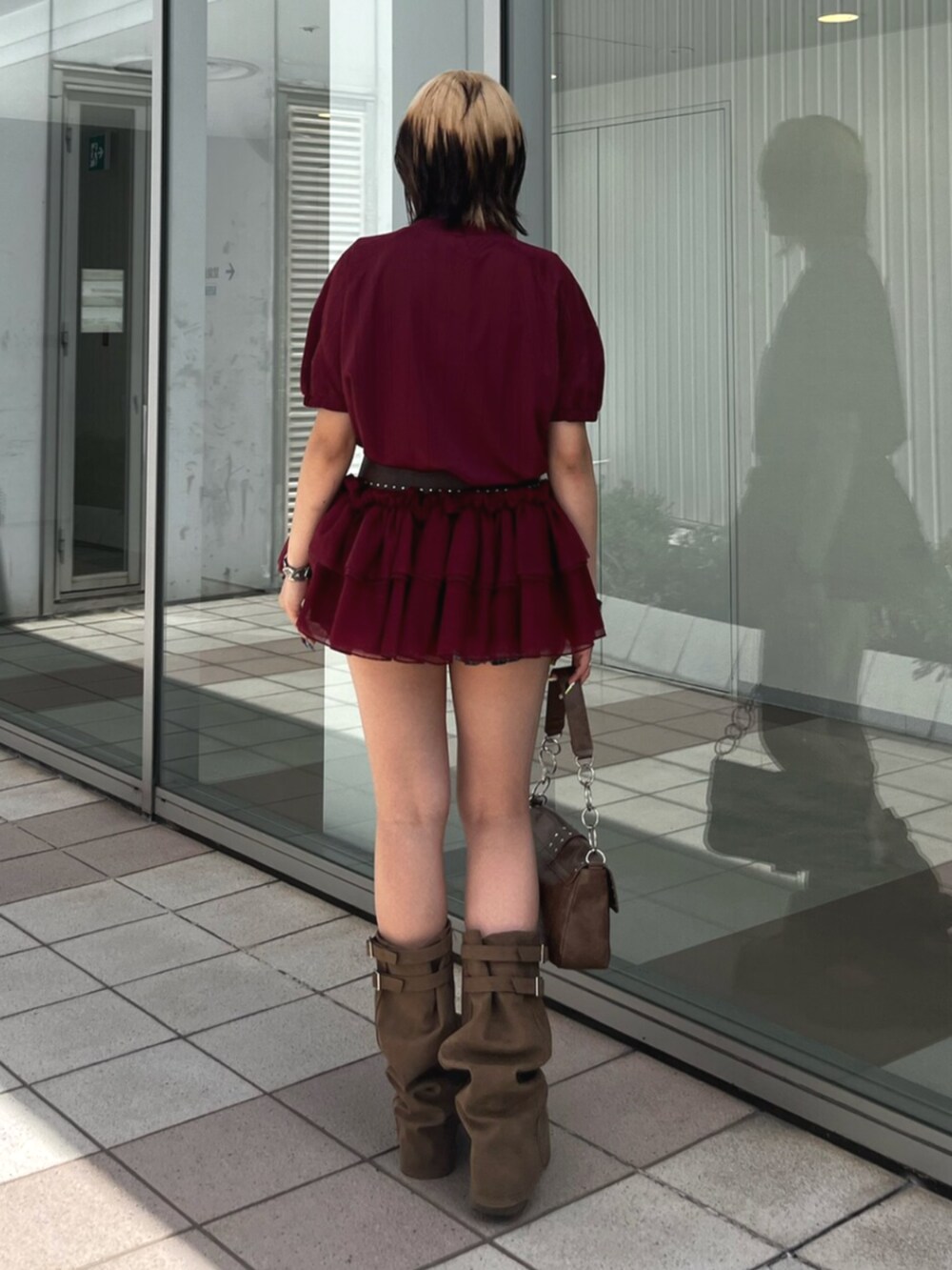 レッド系のワンピース、ブラウン系のハンドバッグ、ブラウン系のサンダルを着用したレディースの春コーディネートの3枚目の写真