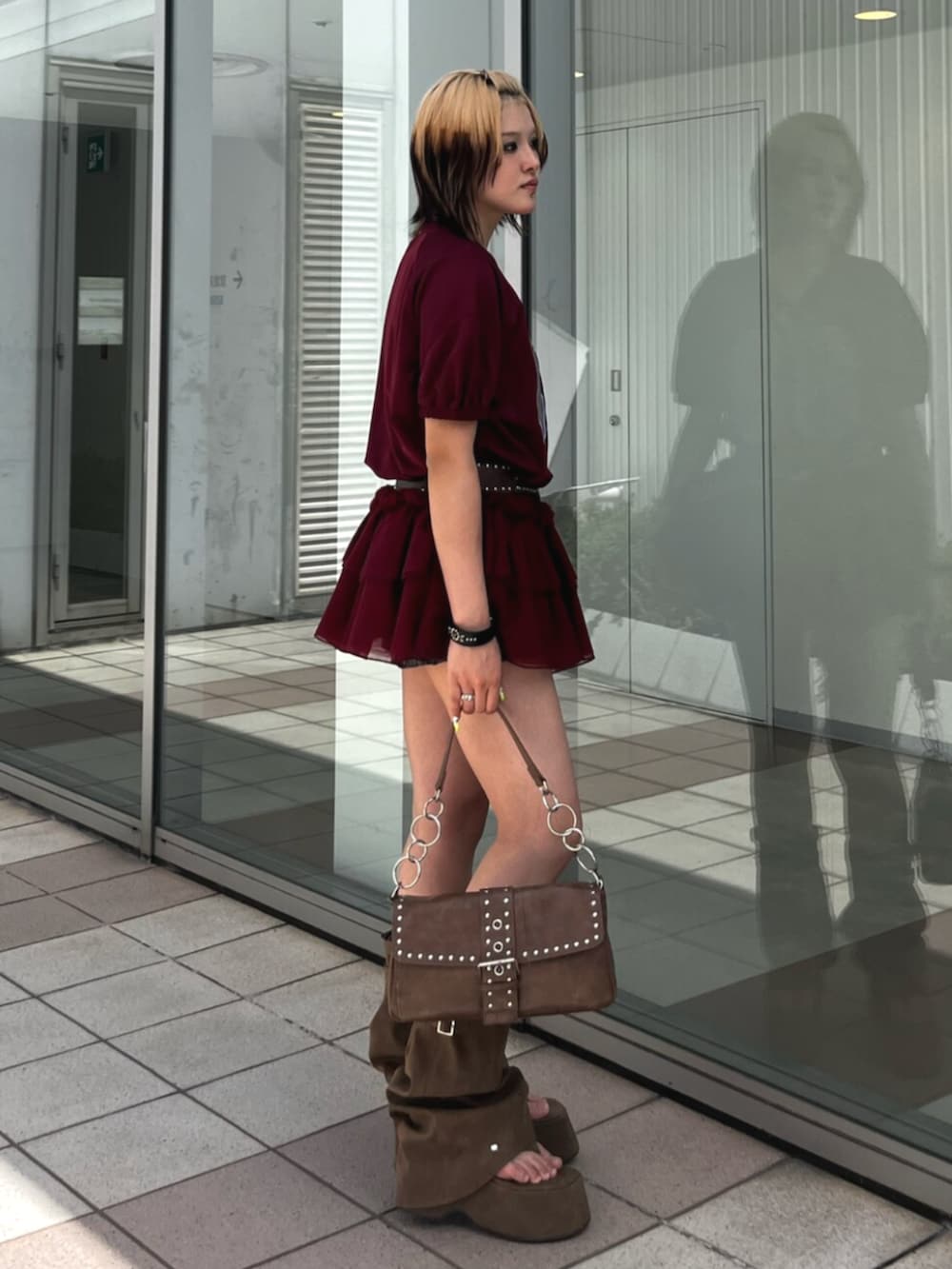 レッド系のワンピース、ブラウン系のハンドバッグ、ブラウン系のサンダルを着用したレディースの春コーディネートの2枚目の写真