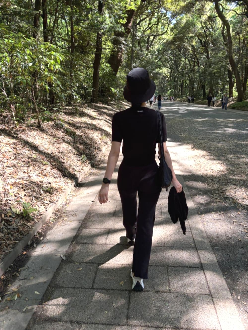 ブラック系のニット/セーター、ブラック系のその他パンツ、ホワイト系のスニーカーを着用したレディースの春コーディネートの2枚目の写真