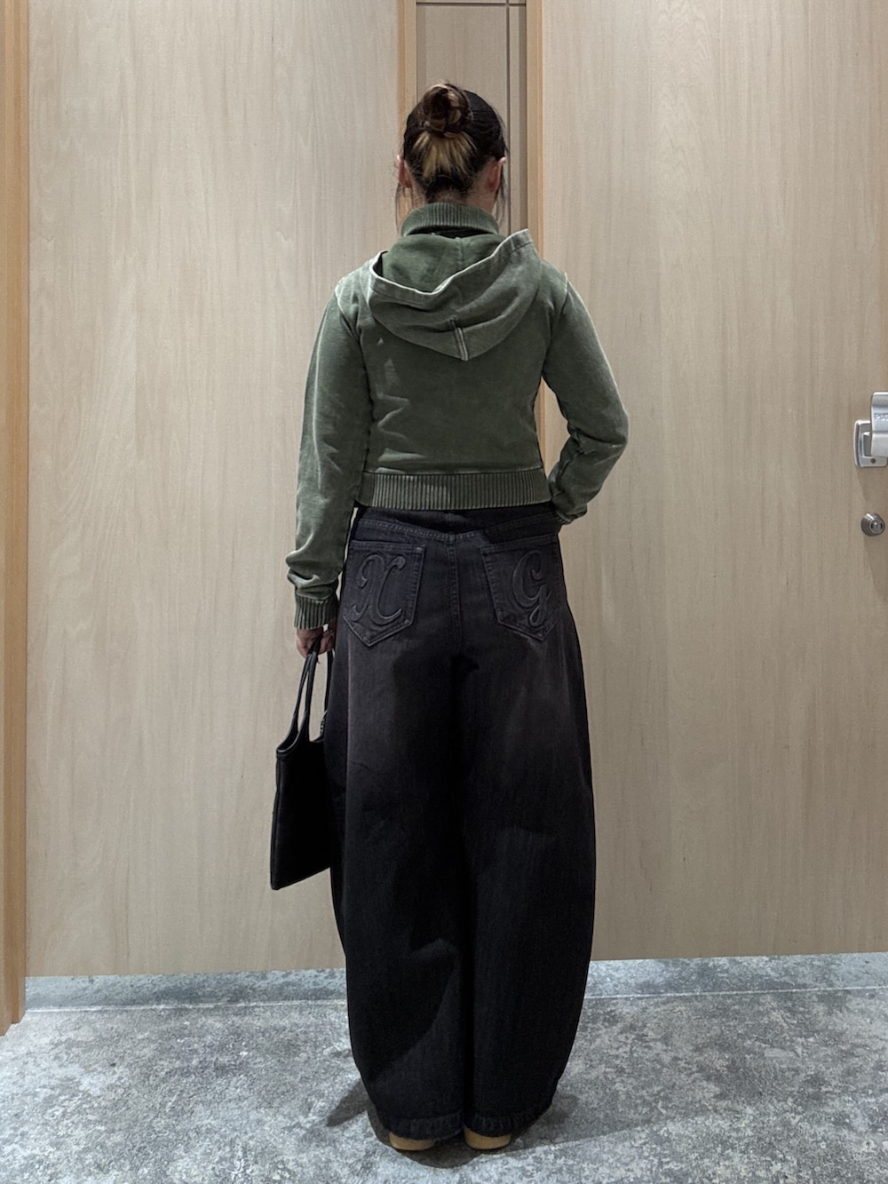 ブラック系のデニムパンツ、グリーン系のパーカー、ブラック系のショルダーバッグを着用したレディースの秋コーディネートの2枚目の写真