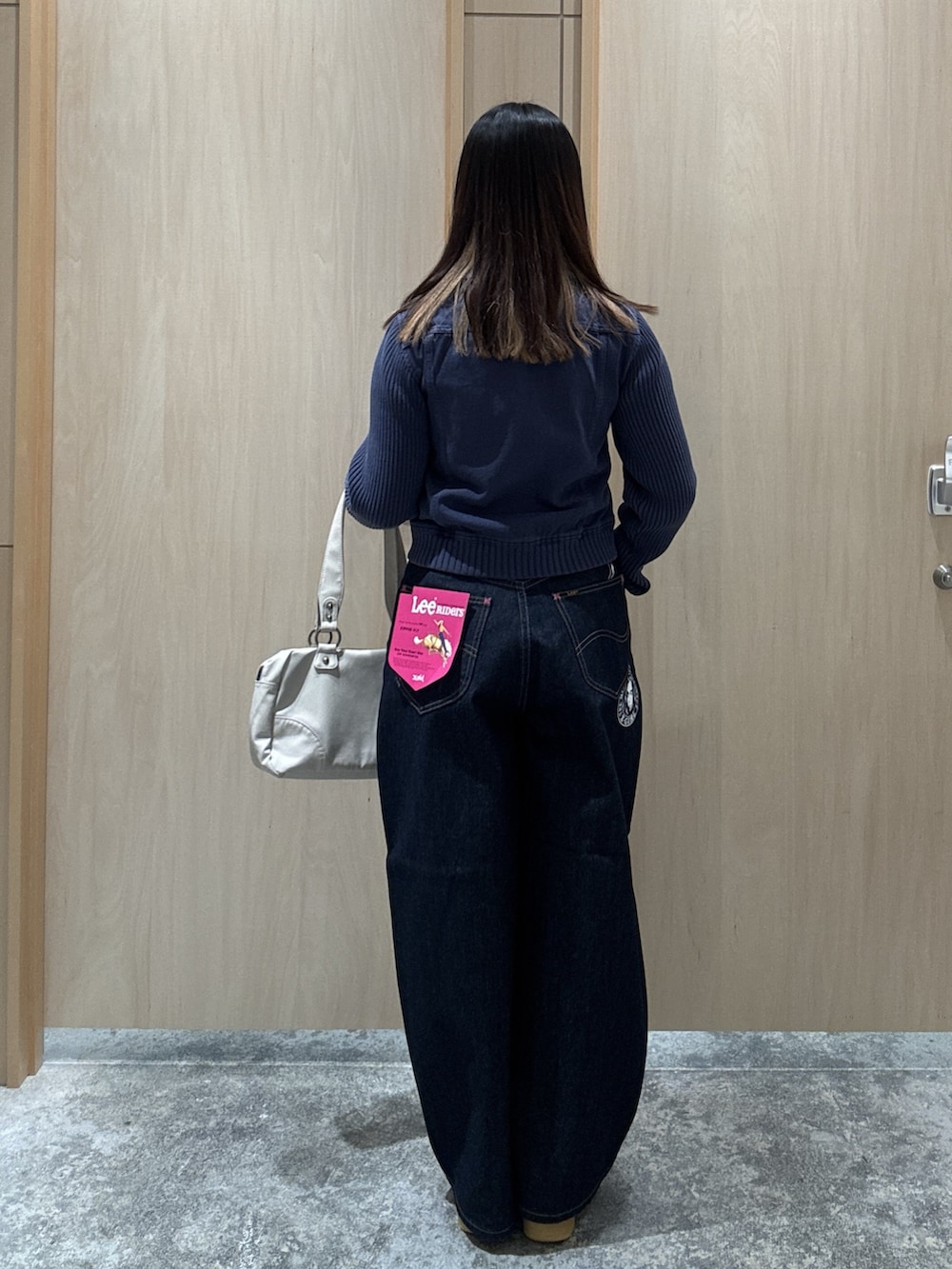 ブルー系のブルゾン、ブルー系のデニムパンツ、ホワイト系のハンドバッグを着用したレディースの夏コーディネートの2枚目の写真