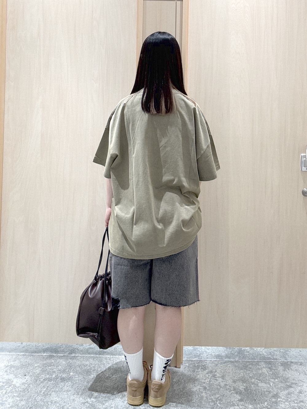 グリーン系のワンピース、ブラック系のデニムパンツ、ブラウン系のバックパック/リュックを着用したレディースの夏コーディネートの2枚目の写真