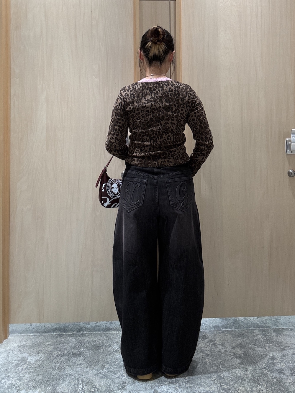 ブラック系のデニムパンツ、レッド系のハンドバッグ、ベージュ系のTシャツ/カットソーを着用したレディースの秋コーディネートの2枚目の写真