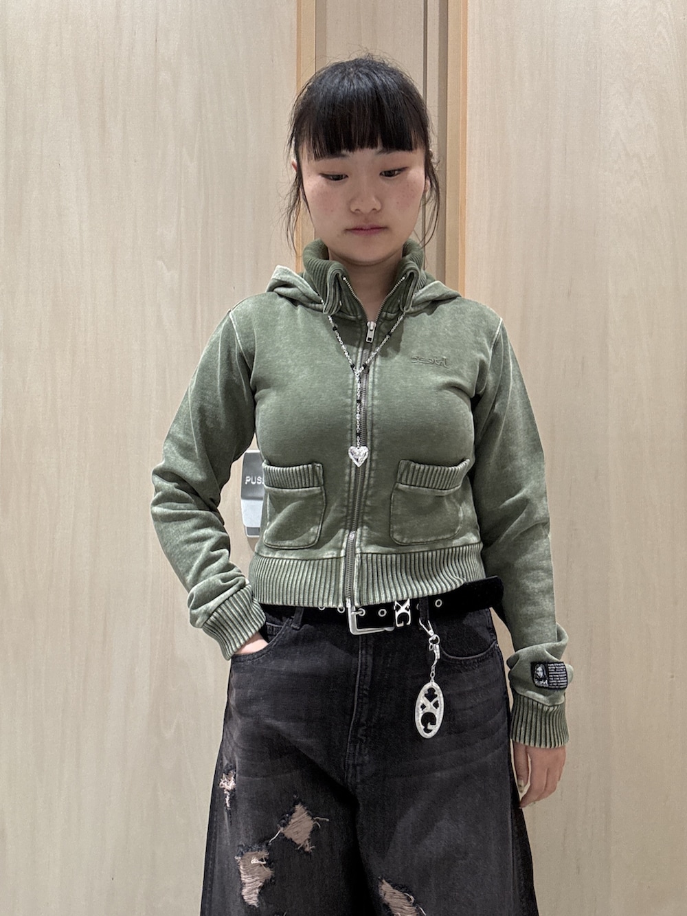 ブラック系のデニムパンツ、グリーン系のパーカー、ブラック系のショルダーバッグを着用したレディースの秋コーディネートの3枚目の写真