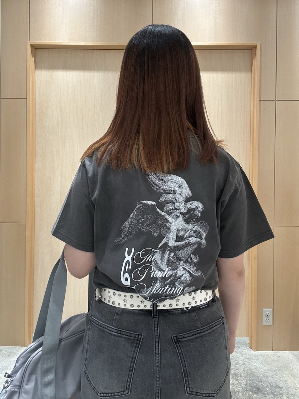 ブラック系のデニムスカート、ブラック系のTシャツ/カットソー、グレー系のハンドバッグを着用したレディースの夏コーディネートの4枚目の写真