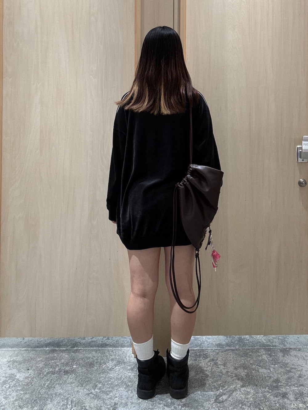 ブラック系のワンピース、ブラウン系のバックパック/リュック、ブルー系のデニムパンツを着用したレディースの秋コーディネートの2枚目の写真