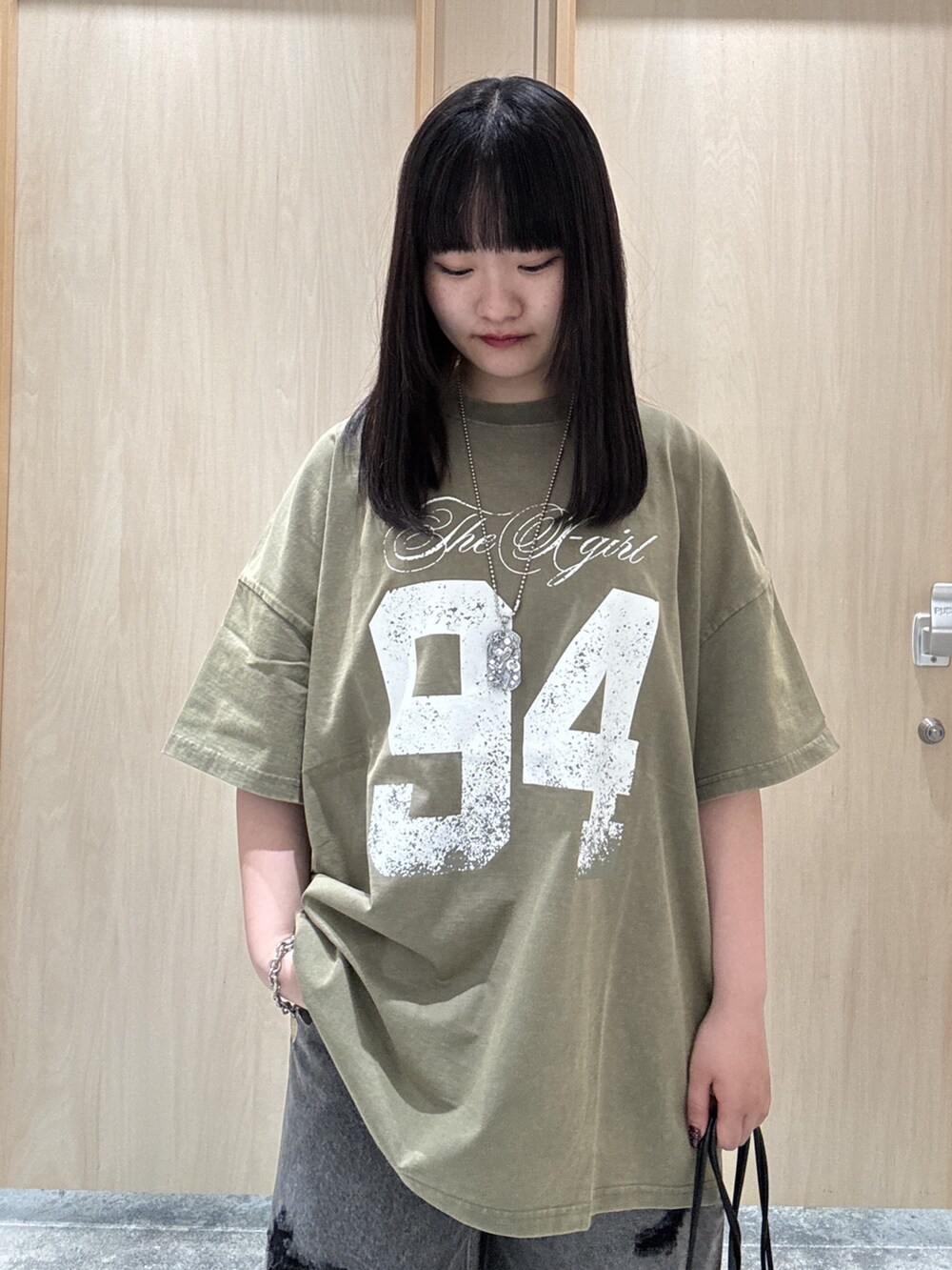 グリーン系のワンピース、ブラック系のデニムパンツ、ブラウン系のバックパック/リュックを着用したレディースの夏コーディネートの3枚目の写真