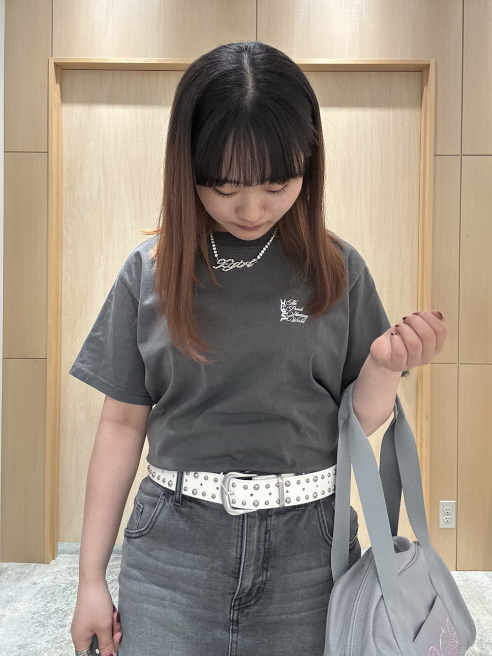 ブラック系のデニムスカート、ブラック系のTシャツ/カットソー、グレー系のハンドバッグを着用したレディースの夏コーディネートの3枚目の写真