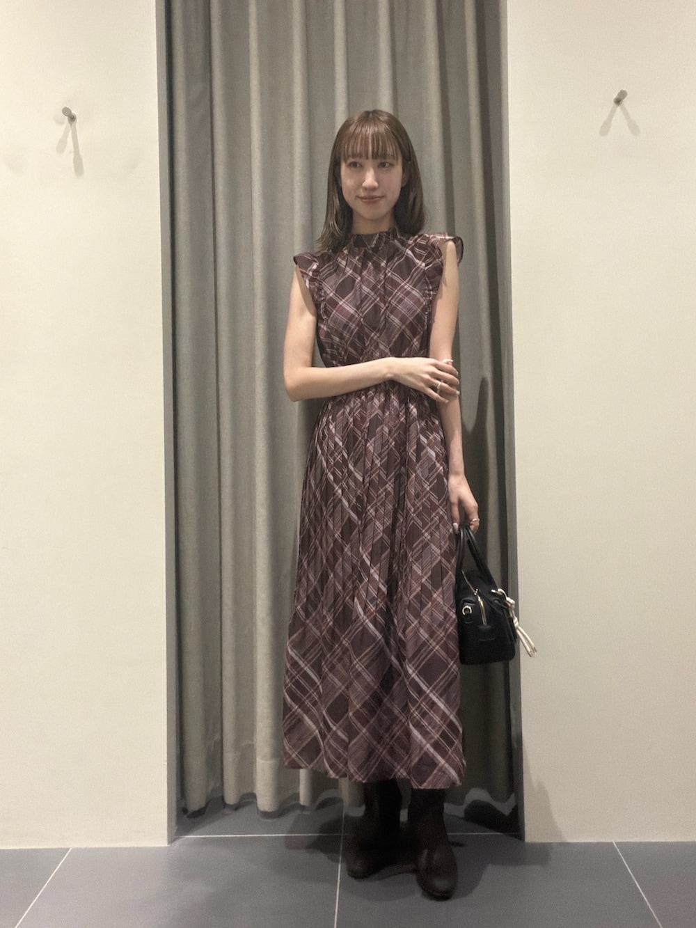 ブラウン系のワンピース、ブラック系のボストンバッグ、ブラウン系のブーツを着用したレディースの夏コーディネートの4枚目の写真