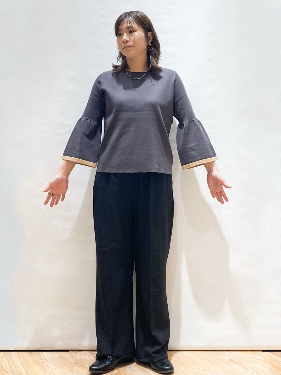 グレー系のニット/セーター、ブラック系のその他パンツ、ベージュ系のトートバッグを着用したレディースの秋コーディネートの2枚目の写真