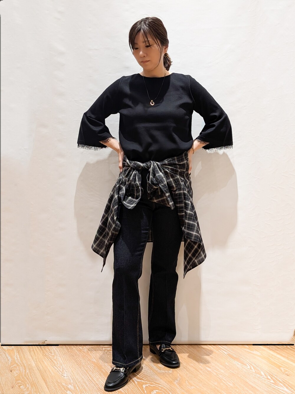 グレー系のシャツ/ブラウス、ブラック系のニット/セーター、ブルー系のデニムパンツを着用したレディースの秋コーディネートの3枚目の写真