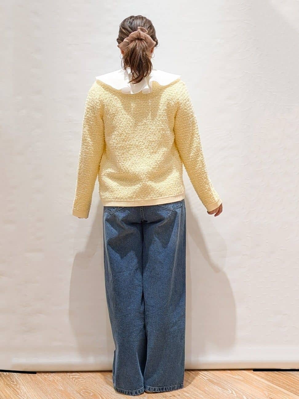 イエロー系のカーディガン/ボレロ、ホワイト系のシャツ/ブラウス、ブルー系のデニムパンツを着用したレディースの冬コーディネートの3枚目の写真