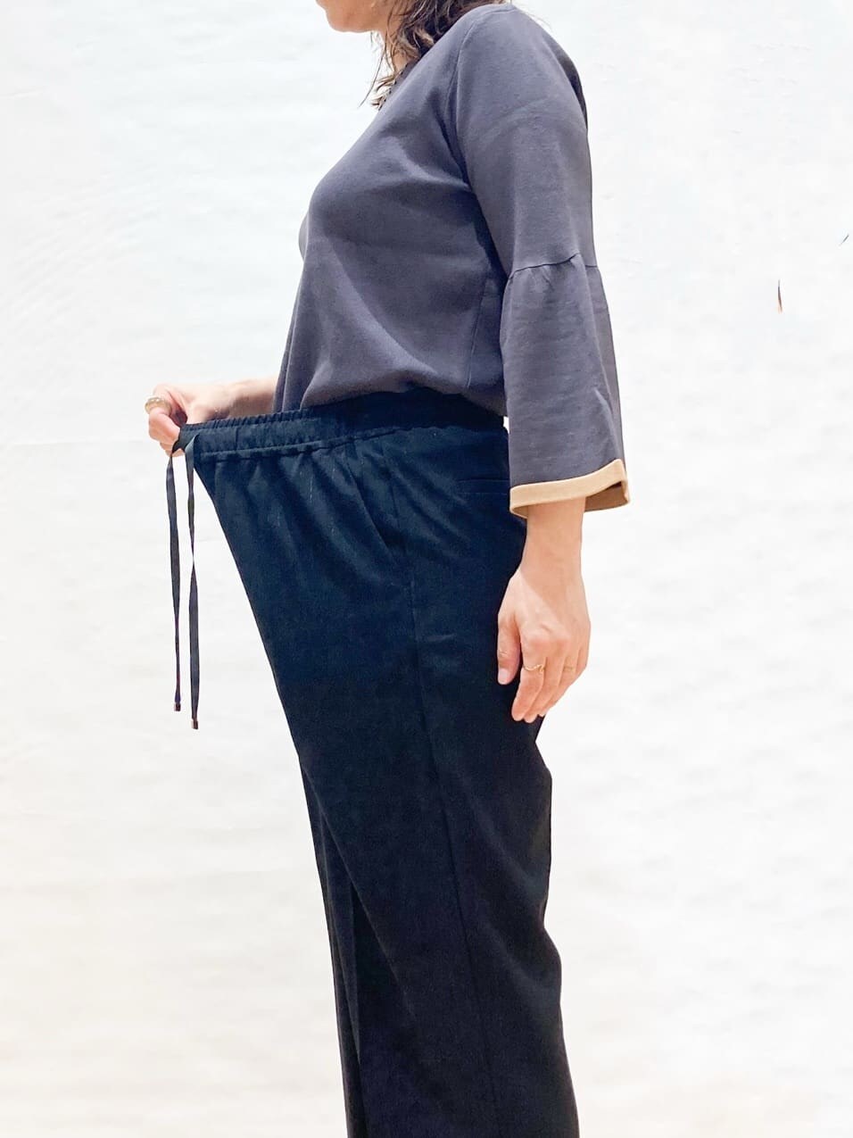 グレー系のニット/セーター、ブラック系のその他パンツ、ベージュ系のトートバッグを着用したレディースの秋コーディネートの4枚目の写真