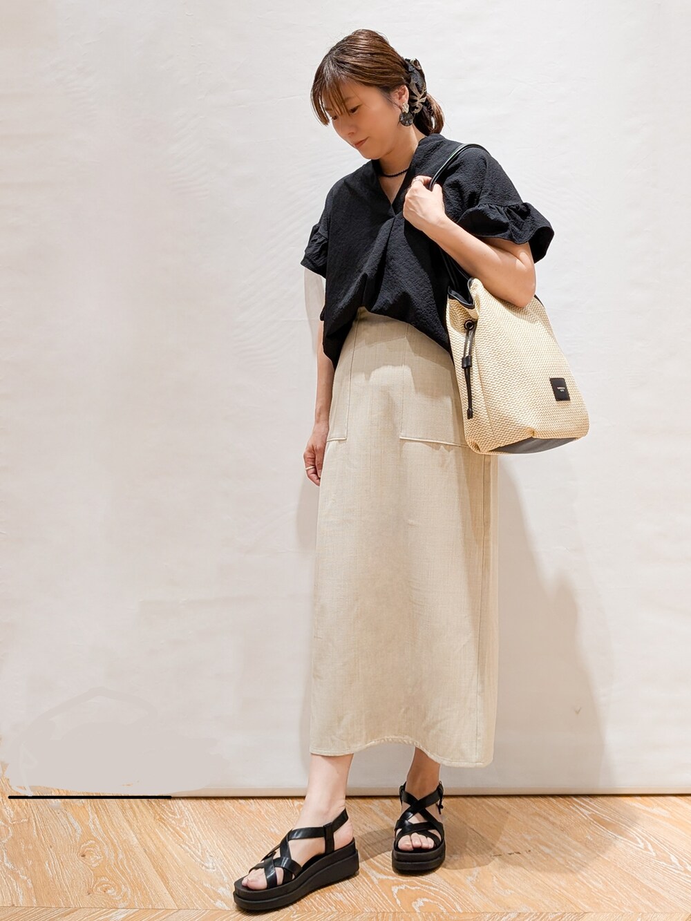 ブラック系のシャツ/ブラウス、ベージュ系のスカート、ホワイト系のトートバッグを着用したレディースの春コーディネートの2枚目の写真