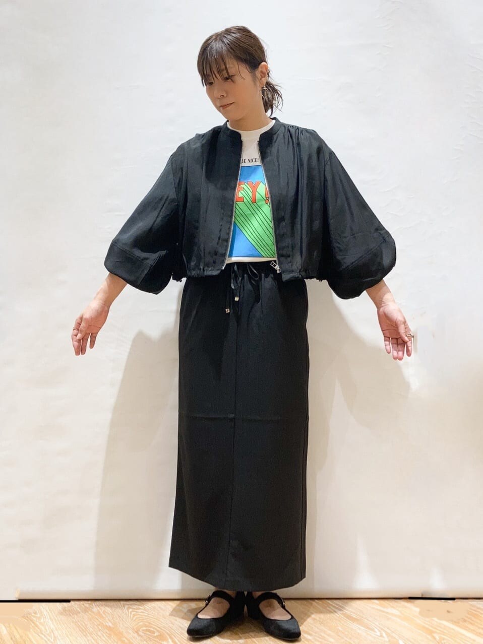 ブラック系のブルゾン、ホワイト系のTシャツ/カットソー、ブラック系のスカートを着用したレディースの夏コーディネートの2枚目の写真