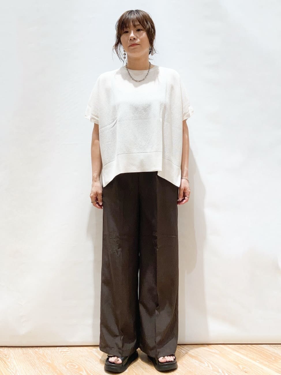ホワイト系のニット/セーター、ブラウン系のその他パンツ、ブラック系のトートバッグを着用したレディースの夏コーディネートの3枚目の写真