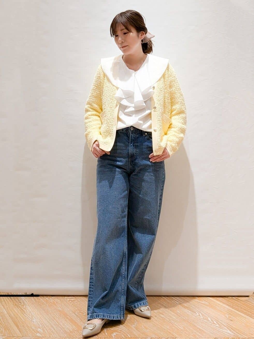 イエロー系のカーディガン/ボレロ、ホワイト系のシャツ/ブラウス、ブルー系のデニムパンツを着用したレディースの冬コーディネートの2枚目の写真