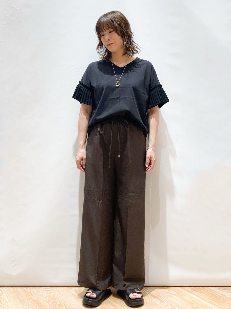 ブラック系のTシャツ/カットソー、ブラウン系のその他パンツ、ブラック系のショルダーバッグを着用したレディースの夏コーディネートの2枚目の写真